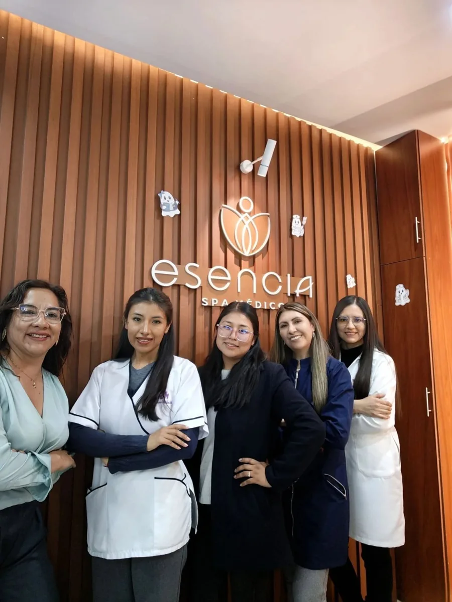 Equipo de Esencia frente al muro de madera con el logo